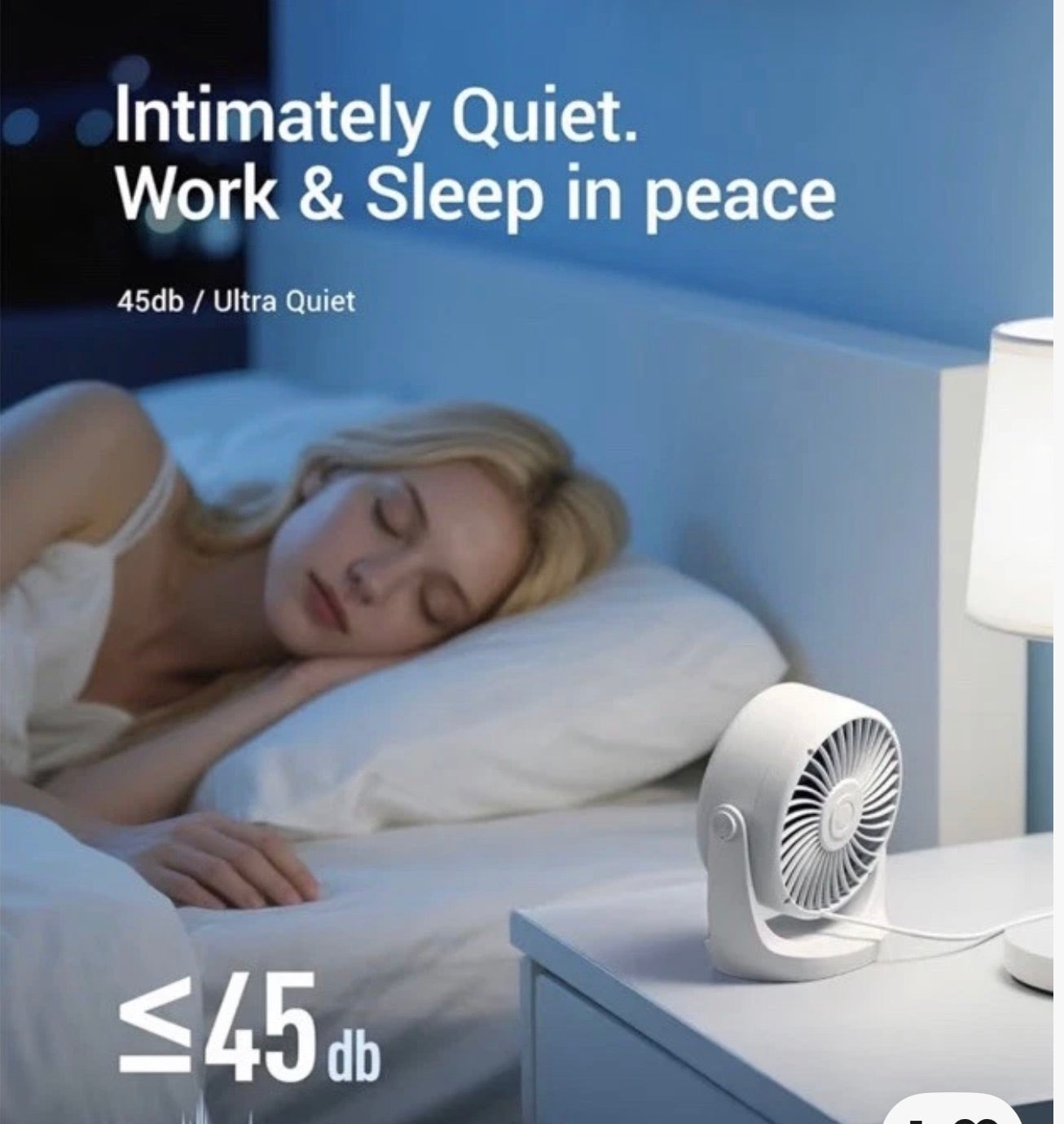 A small white desk fan sits on a bedside table next to a lit lamp in a bedroom, with a sleeping woman in bed in the background. Text on the image reads 'Intimately Quiet.
