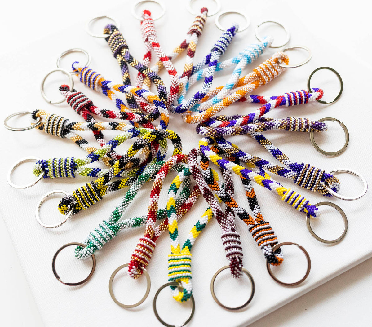 Colorful braided keychains arranged in a circular pattern on a white surface.